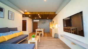 A modern living room with a sofa, coffee table, and a dining area with a table and chairs. - Charcoal Panwa Beach (Wichit)