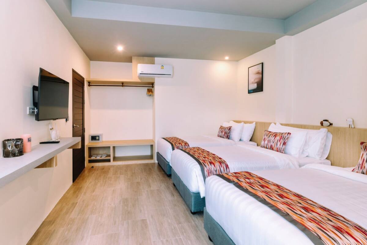 Une chambre d’hôtel avec deux lits, une télévision, un bureau et une étagère avec quelques objets.