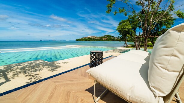 A poolside lounge area with a view of the ocean and a distant island. - Charcoal Panwa Beach (Wichit)