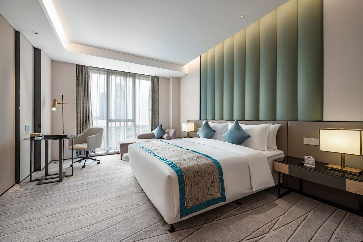 Ein modernes Hotelzimmer mit einem großen Bett, einem Schreibtisch und einem Stuhl.