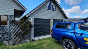 A residential house with a garage, a blue SUV parked in front, and a clear sky. - Private holiday home (Twizel)