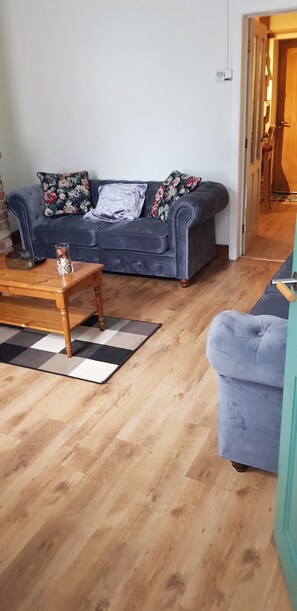 Una sala de estar con un sofá gris, una mesa de centro de madera y un tapete a cuadros.
