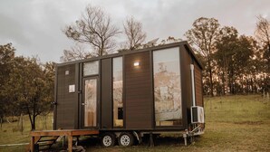 Una cabaña pequeña y moderna con puerta corredera, una cama y un panel solar en el techo.