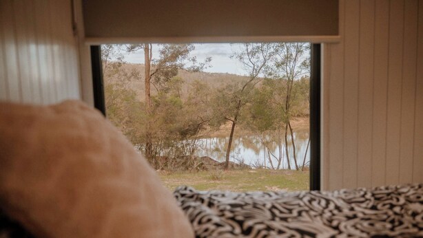 Una habitación con vista a un paisaje natural que incluye árboles y una masa de agua.
