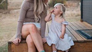 Una mujer y un niño sentados en un banco de madera al aire libre.