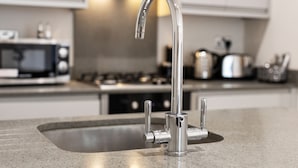 A kitchen with a stainless steel sink, a modern faucet, a microwave, and a stove. - Brand New Unique 2 Bedroom Apartment (Reading)