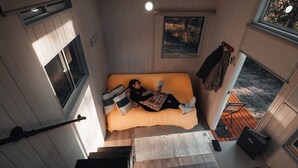 A compact room with a bed, a window, and a door leading to an outdoor area. - Raintree Farm Stay by Tiny Away (Sarsfield)