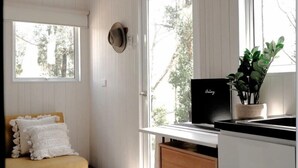 A room with a wooden bench, a hat on the wall, a black laptop on a counter, and a potted plant. - Raintree Farm Stay by Tiny Away (Sarsfield)
