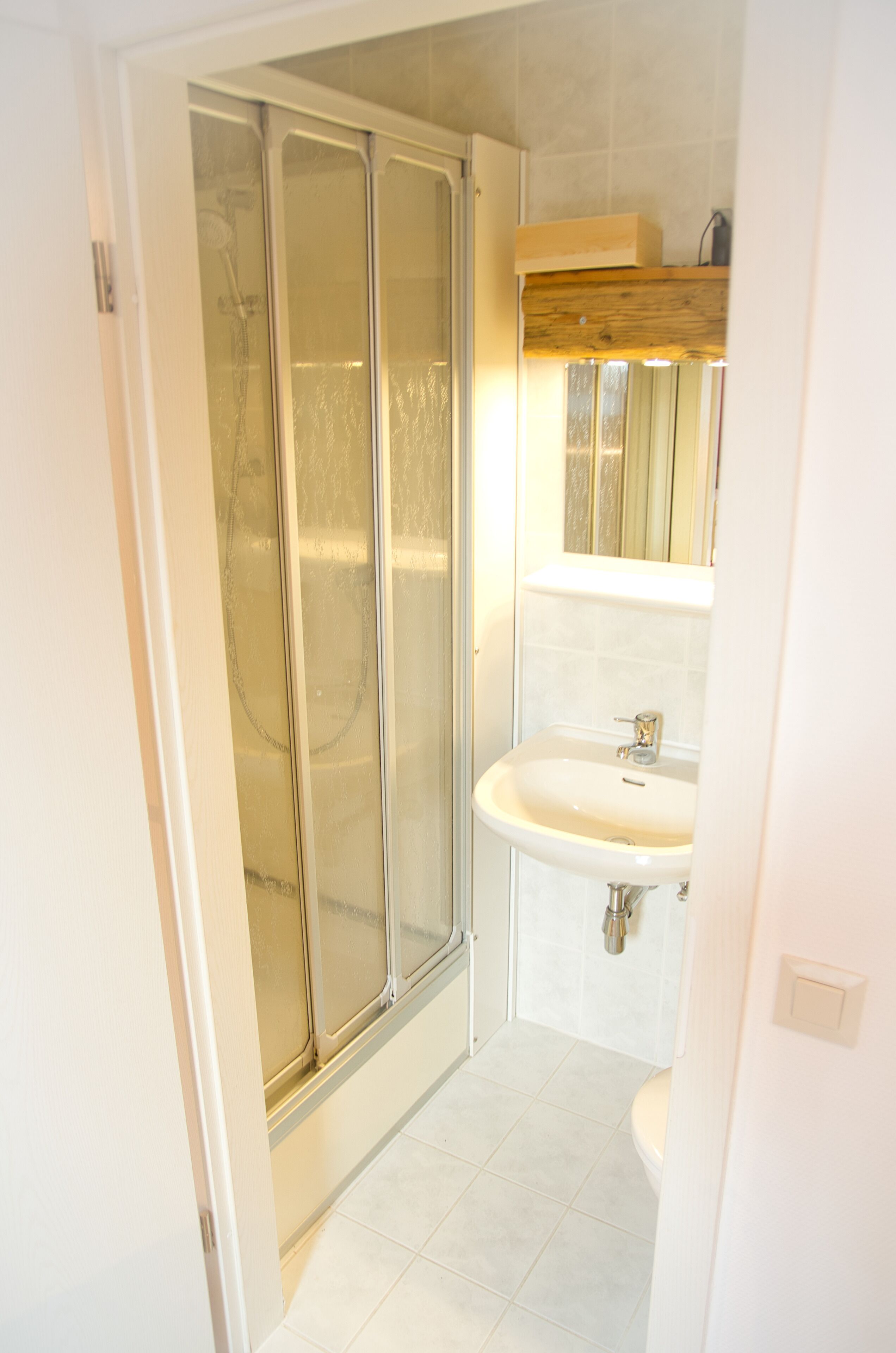 Un baño con ducha, lavabo y espejo.