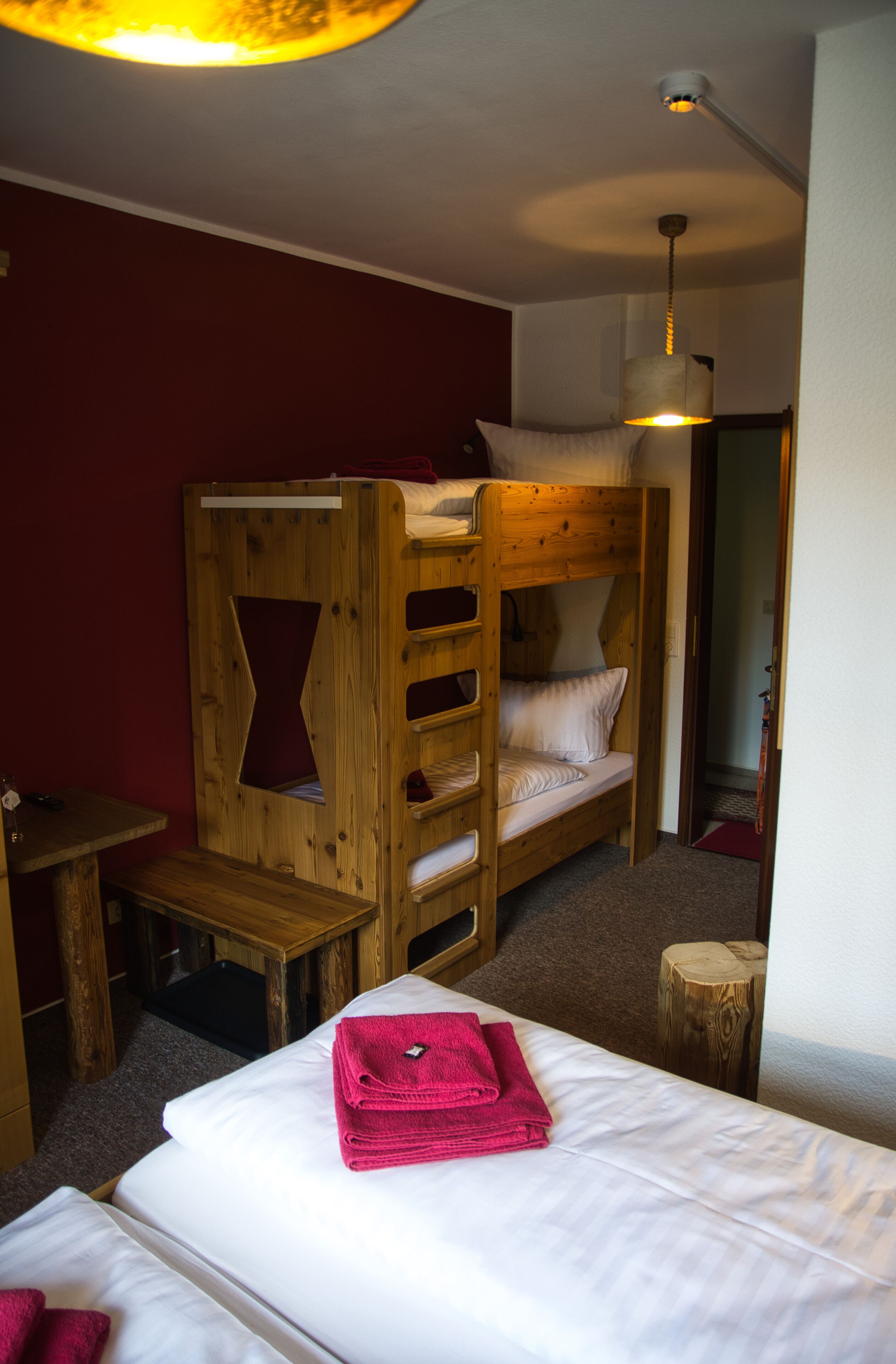 Una habitación con una litera, una pequeña mesa de madera y una cama con una toalla rosa.