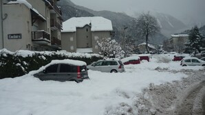 Una strada innevata con auto parcheggiate e un edificio con la scritta "Ondines".