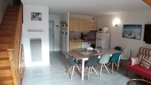 Un ambiente compatto con angolo ristoro, angolo cottura e divano.