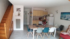 Una cucina moderna con mobili in legno, un'area pranzo con tavolo e sedie, e una scala che conduce a un altro piano.