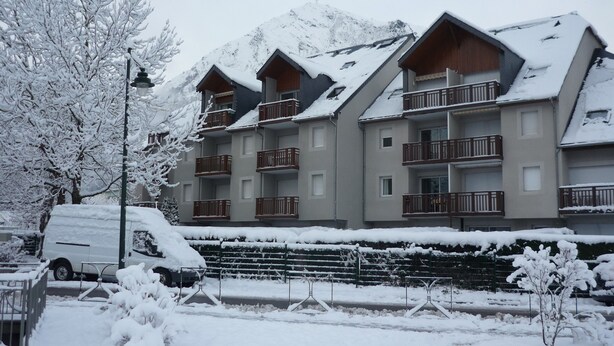 Un hotel a più piani con balconi, un paesaggio innevato e una montagna sullo sfondo.