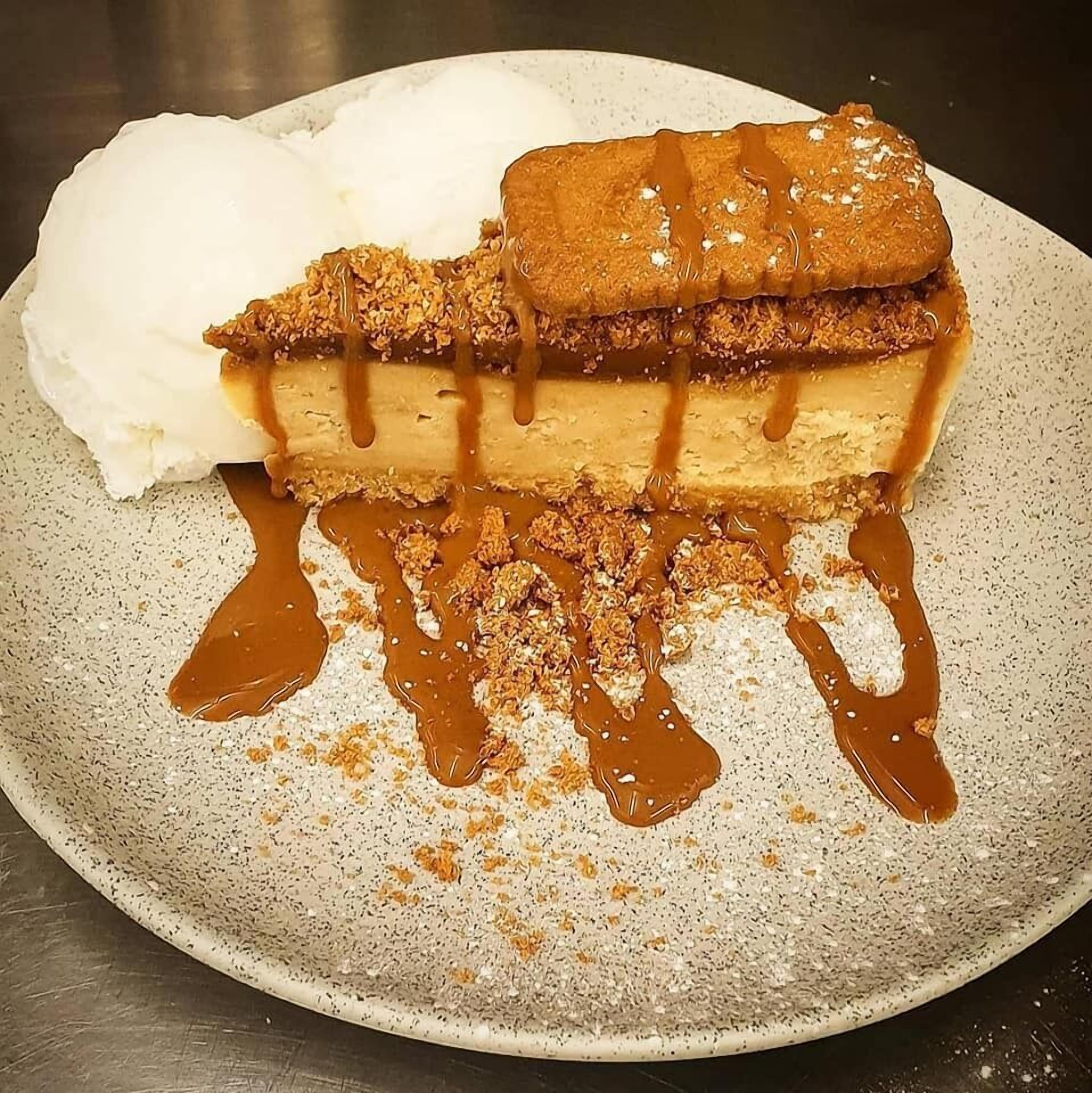 A dessert with caramel sauce and crumbled topping on a plate.