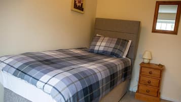 Une chambre à coucher comprenant un lit, une table de chevet, une lampe et un miroir fixé au mur.