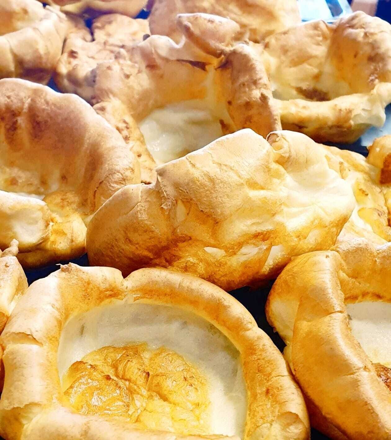 A close-up of Yorkshire puddings with a golden-brown exterior and a soft, fluffy interior.