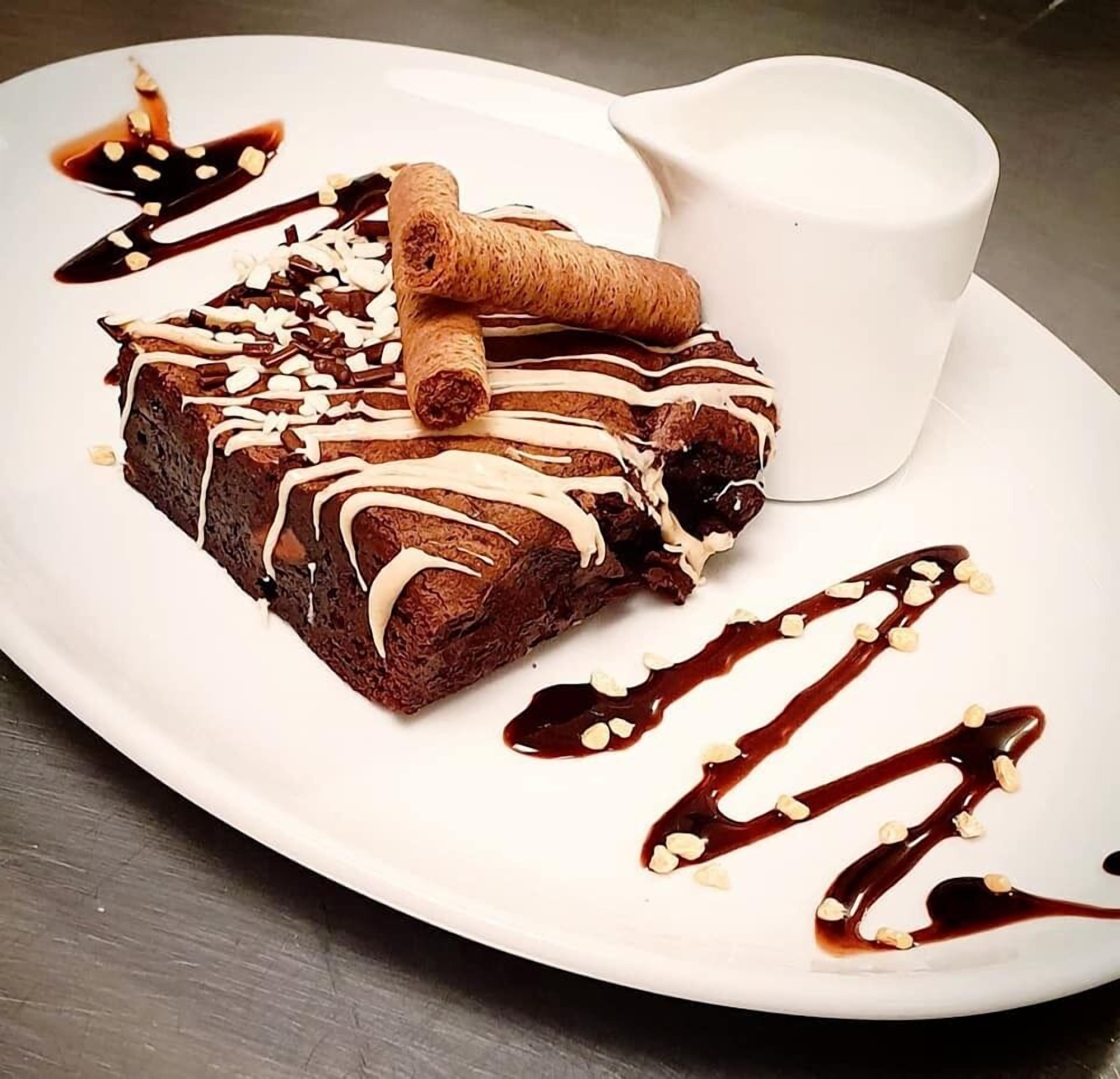 En desserttallerken med et stykke kage, en roulade og en lille kop.