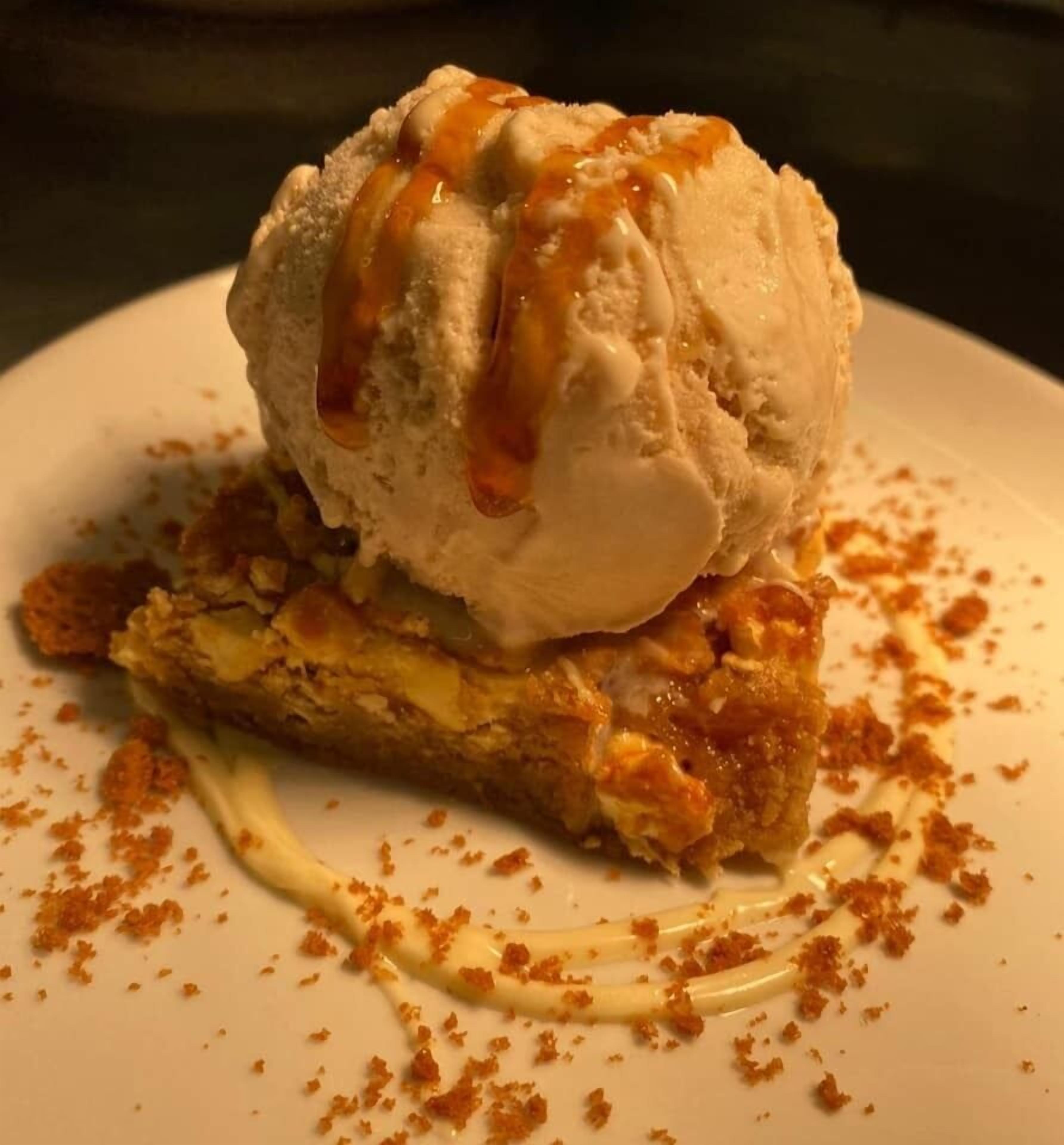 A dessert with ice cream and caramel sauce on a plate.