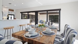 A modern dining area with a wooden table set for six, surrounded by striped chairs.