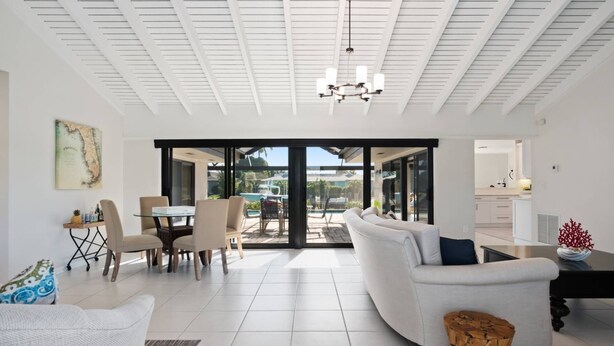 A spacious living room with a large sofa, a dining area, and a view of a pool and outdoor space.