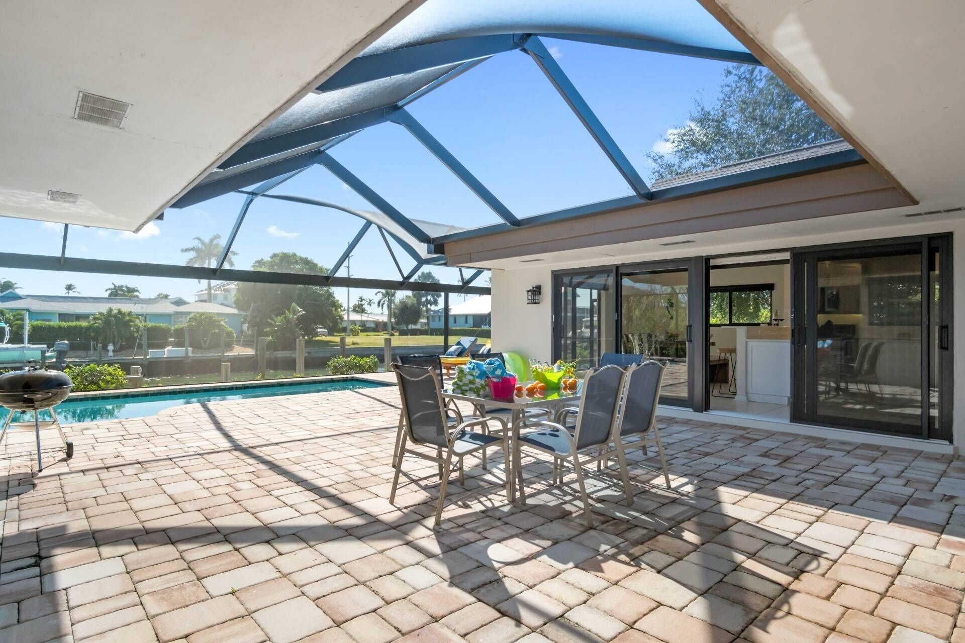 A covered patio with a pool, outdoor furniture, and a view of the neighborhood.