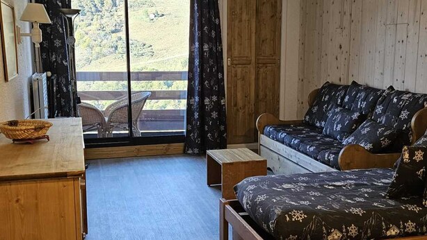 Ein gemütliches Zimmer mit einem hölzernen Bett, einem kleinen Holztisch und einem Fenster mit Blick auf eine grüne Landschaft.