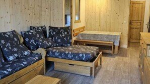 Ein gemütliches Zimmer mit einer Holzcouch, einem Bett und einem kleinen Tisch.
