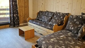Ein gemütliches Zimmer mit einer Holzcouch und einem kleinen Holztisch.