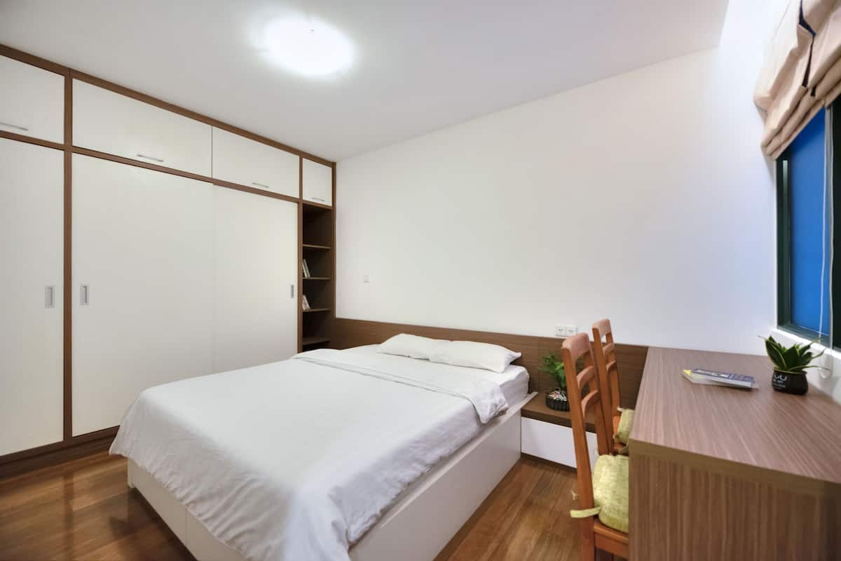 A bedroom with a bed, a desk, a chair, and a window.