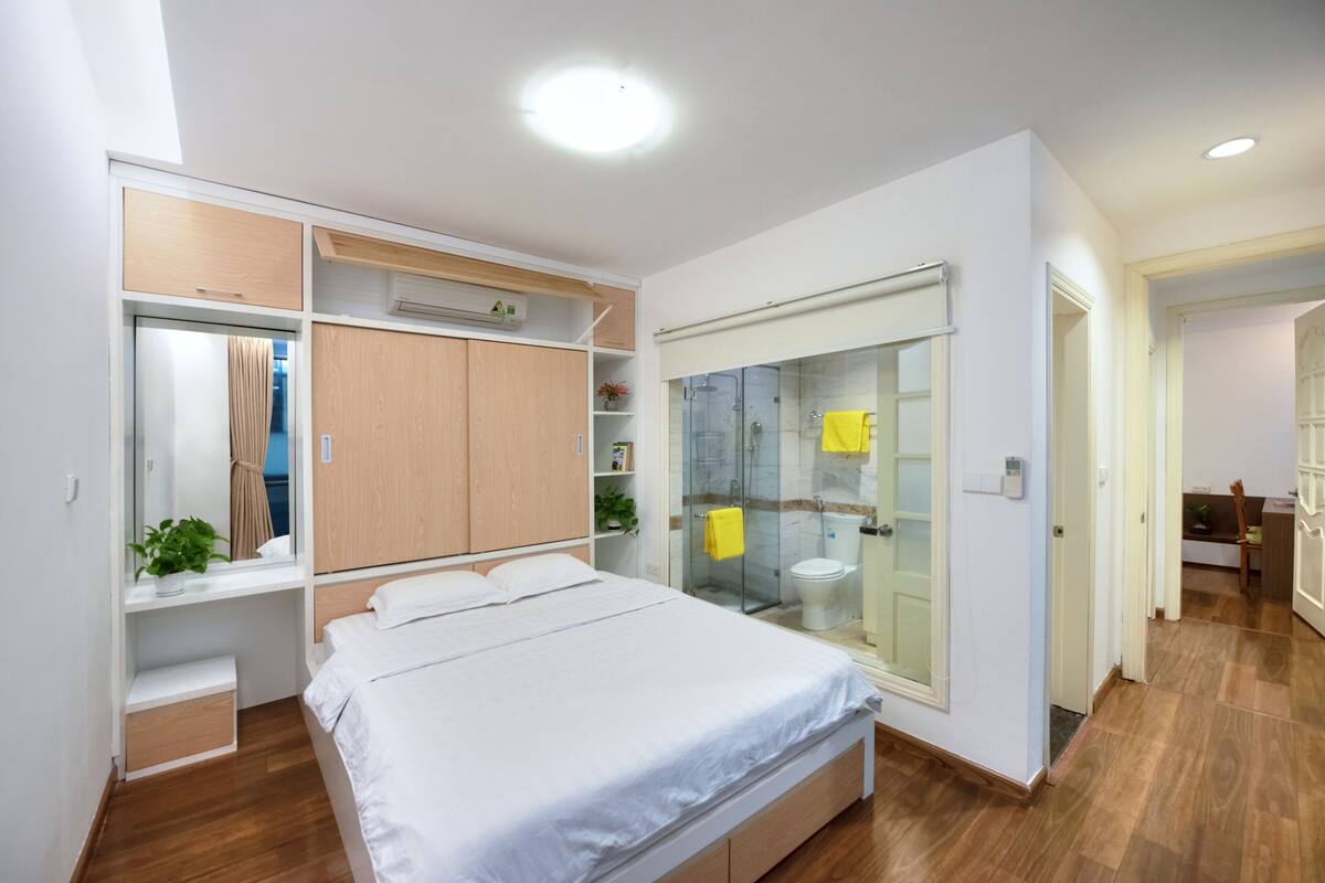 A modern bedroom with a bed, built-in wardrobe, and a glass shower enclosure.