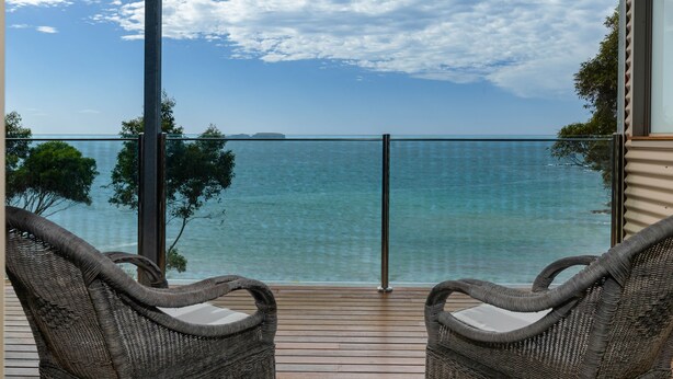 Un balcon avec des fauteuils en osier et vue sur la mer.