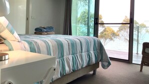 Une chambre à coucher avec un lit, un téléviseur fixé au mur et une vue sur l’extérieur grâce à une porte coulissante.