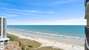 Une vue sur la plage depuis un immeuble de grande hauteur, avec un ciel dégagé.