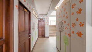 A hallway with wooden doors and walls decorated with leaf patterns. - OYO 75362 Swagath Home (Bangkok)