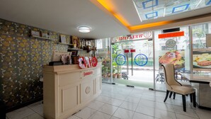 A restaurant interior with a reception desk labeled "Swagath," a tiled floor, and a view of the street through glass doors. - OYO 75362 Swagath Home (Bangkok)