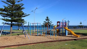 A playground with swings, a slide, and climbing structures near a body of water. - Paradise @ Port Hughes, 500M walk to beach, ALL LINEN & TOWELS PROVIDED (Port Hughes)