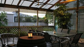 An outdoor patio with a glass table and chairs, surrounded by a wooden fence and greenery. - Paradise @ Port Hughes, 500M walk to beach, ALL LINEN & TOWELS PROVIDED (Port Hughes)