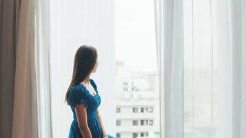 A person sitting by a window with a view of buildings outside.