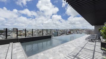 Una piscina infinita en la azotea con vistas a la ciudad, un área de estar cubierta y un diseño arquitectónico moderno.