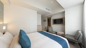 A modern hotel room with a large bed, a desk, a chair, and a television.