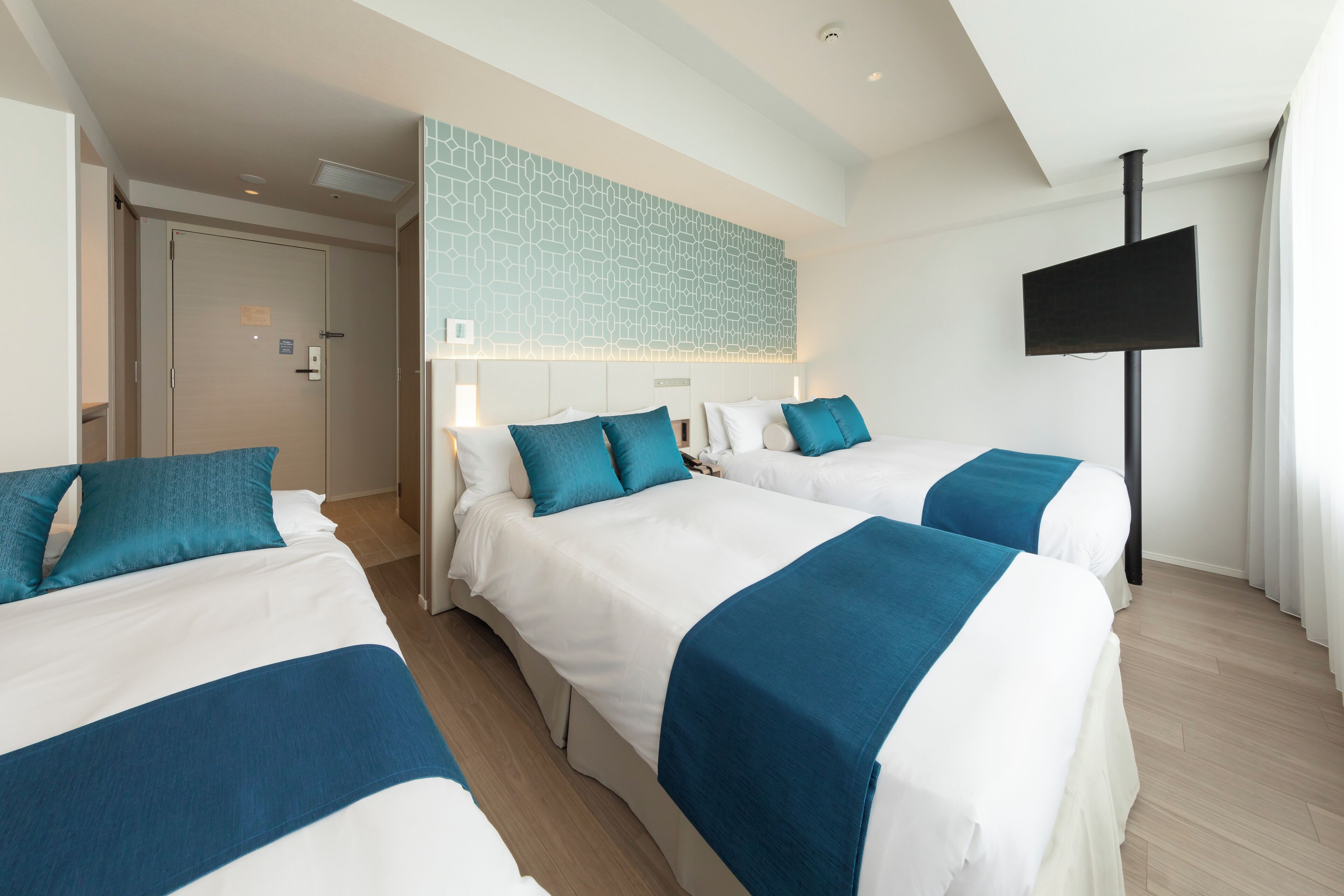 A hotel room with two beds, a TV, and a modern design.