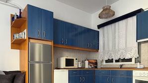 Een moderne keuken met blauwe kastjes, roestvrijstalen apparatuur en een rond geweven vloerkleed.