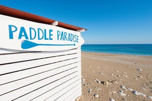 A beachside sign with the text "Paddle Paradise" and a paddle symbol.