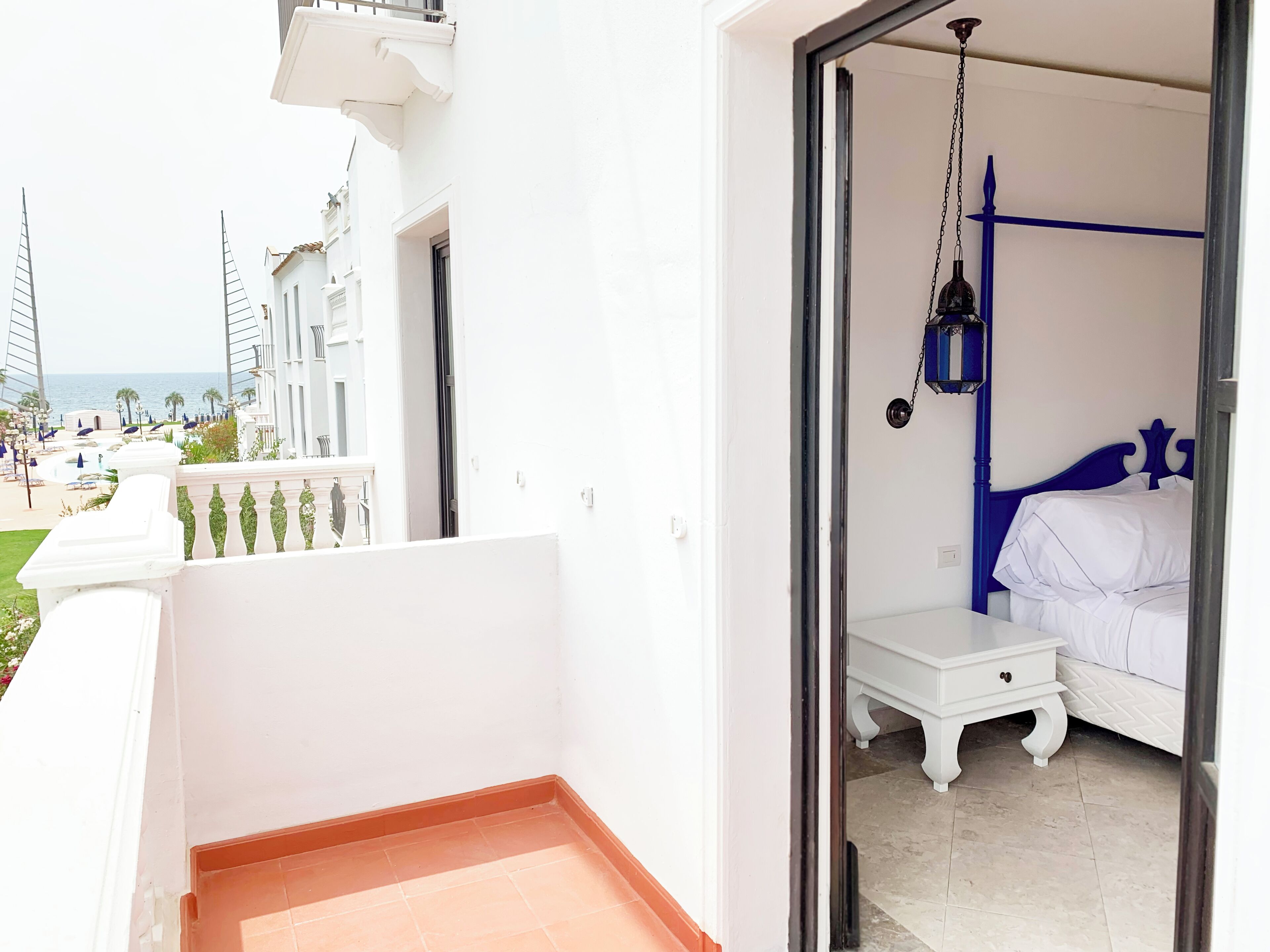 A room with a bed, a nightstand, and a hanging lamp.