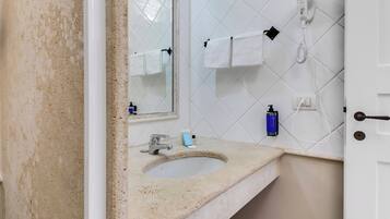 Een badkamer met een wastafel, spiegel, handdoekrek, haardroger en toiletartikelen.