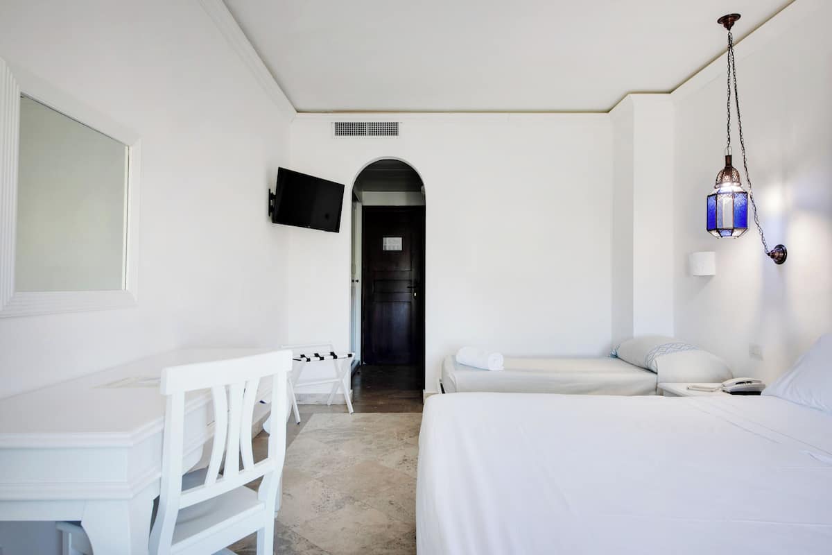 Ein Hotelzimmer mit Bett, Schreibtisch, Sessel, Fernseher und einer Pendelleuchte.