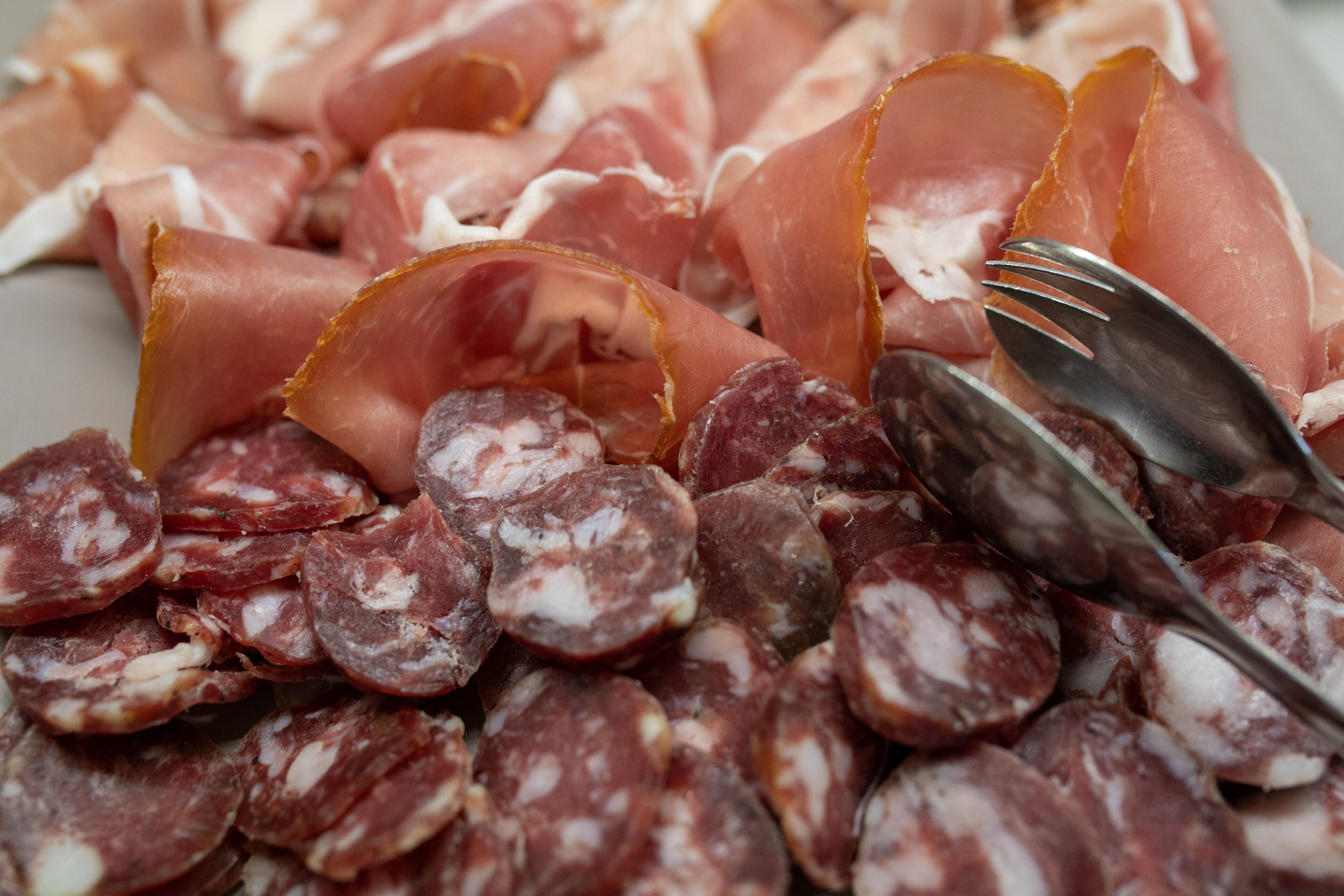 Une variété de charcuteries, notamment des tranches de salami et de jambon cru, disposées sur une assiette.