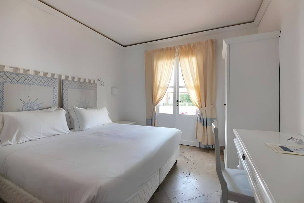 Ein Schlafzimmer mit Bett, Nachttisch, Vorhängen und einer Tür.