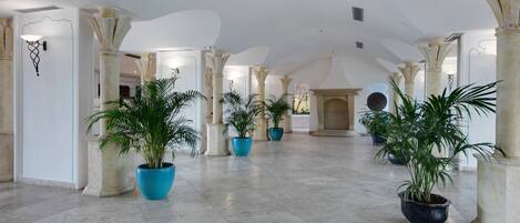 Un interior espacioso con techos altos, columnas clásicas y plantas en macetas.